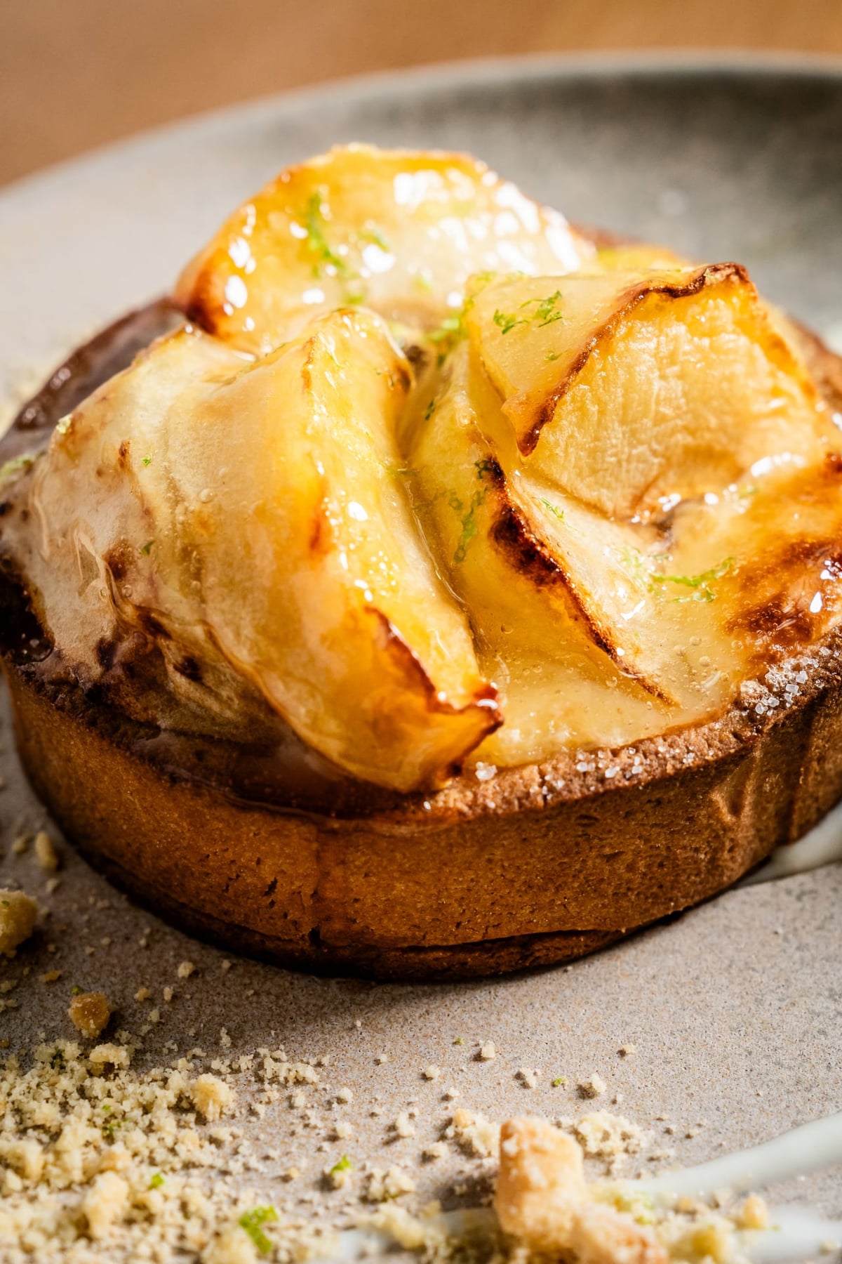 Homemade apple tart with a golden, glossy finish, topped with thin slices of caramelized fruit. The surface features a crisp
