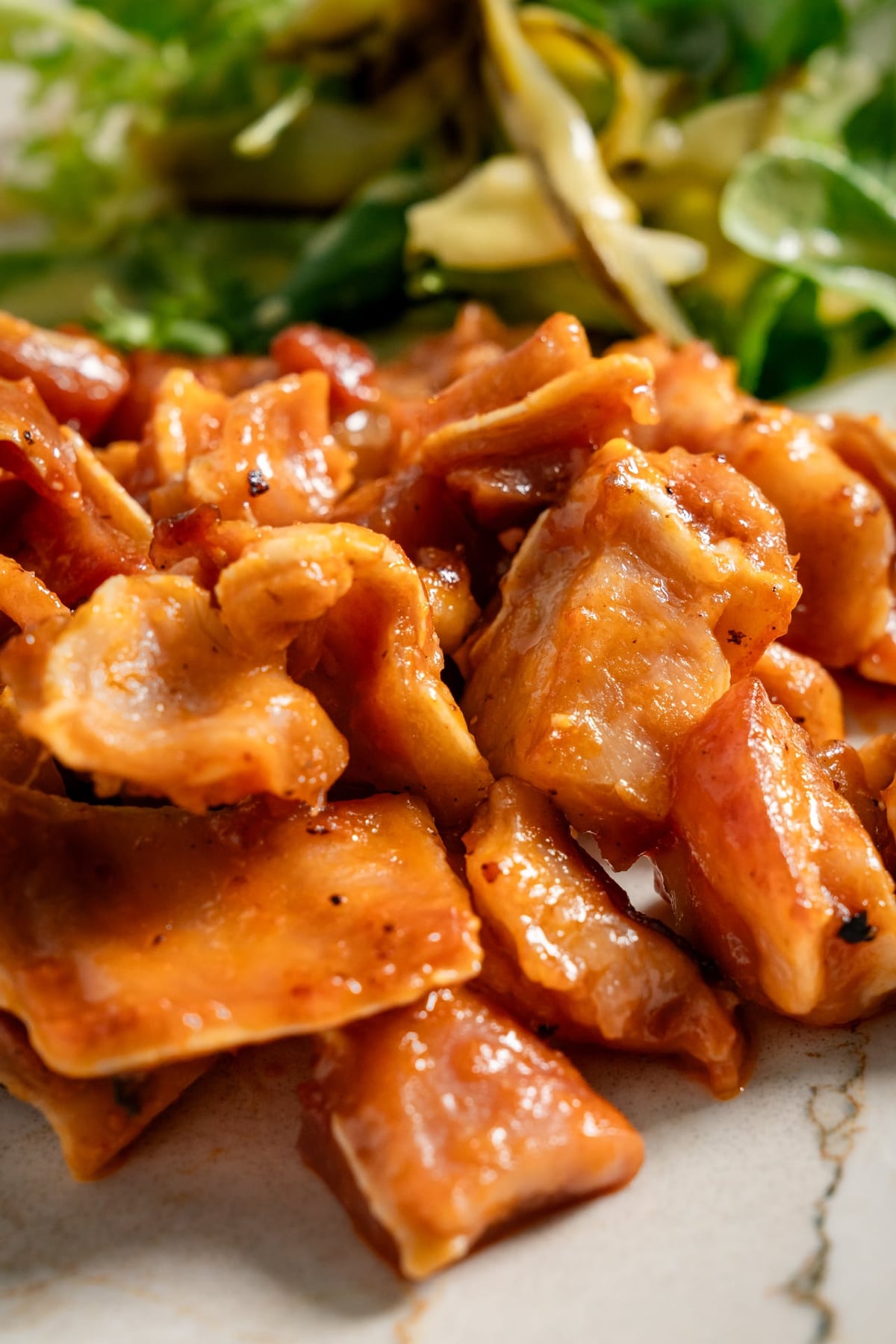 Crispy pieces of “oreja a la brava,” golden brown and smothered in sauce, served with a fresh watercress salad. The dish
