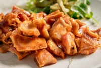 Crispy pieces of “oreja a la brava,” golden brown and smothered in sauce, served with a fresh watercress salad. The warm
