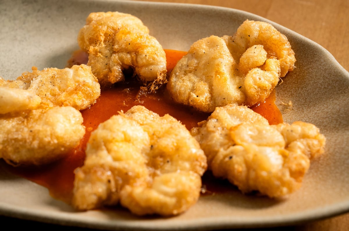 Kokotxas de bacalao crujientes presentadas en una bandeja de papel, doradas y con una textura esponjosa. Este plato destaca