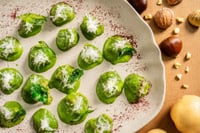Chestnut gnocchi served on a wooden board, accompanied by pieces of fresh and dried chestnuts, as well as aromatic herbs.