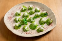 A plate of chestnut gnocchi served on a rustic ceramic platter, garnished with shavings of Parmesan cheese and sprinkled