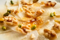 Carpaccio de melon aux copeaux de jambon ibérique, aux grains de poivre vert et à un filet d'huile, au restaurant MATRICE.